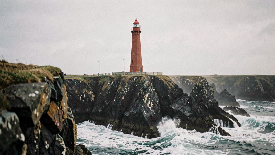 A tall red brick lighthouse above dark twisted cliffs with white water breaking below